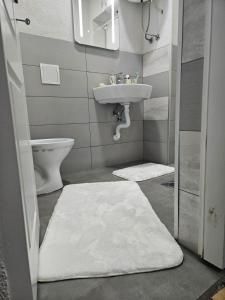 La salle de bains est pourvue d'un lavabo et d'un tapis blanc. dans l'établissement Apartmani Planinsko srce Vlašić, à Šišava