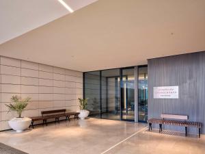 a lobby with benches and plants in a building at Grand Hyatt Kuwait Residences in Kuwait