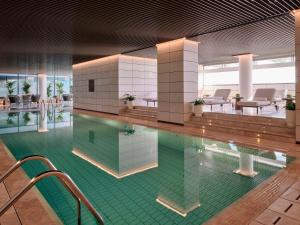 a swimming pool with chairs and tables in a building at Grand Hyatt Kuwait Residences in Kuwait