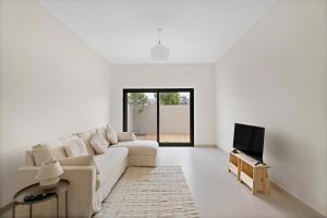 a white living room with a couch and a tv at Lovely 3BR Villa in Dubai EXPO in Dubai