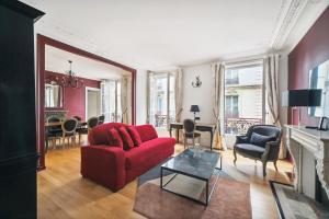 uma sala de estar com um sofá vermelho e cadeiras em Séjours Parisiens / Suite Le Royal / 4* em Paris