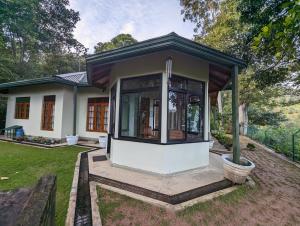 a small house with a front porch with a porch at SunnySide Lodge - Tea Plantation Bungalow in Ella
