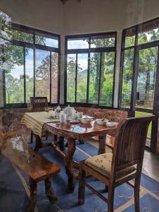 a dining room with a table and chairs and windows at SunnySide Lodge - Tea Plantation Bungalow in Ella