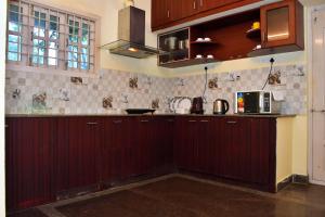 a kitchen with dark wood cabinets and a microwave at Revive Inn Pondy - Rooms & Villa in Puducherry