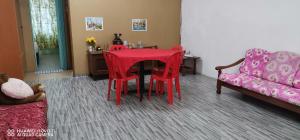 um quarto com uma mesa com cadeiras vermelhas e um sofá em EBH2 Guesthouse em Kampong Alor Gajah
