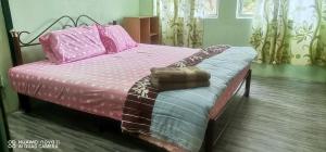 a bedroom with a bed with pink sheets and pillows at EBH2 Guesthouse in Kampong Alor Gajah