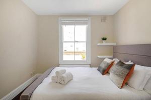 1 dormitorio con 1 cama blanca grande y toallas. en Superb duplex in prime area of London, en Londres