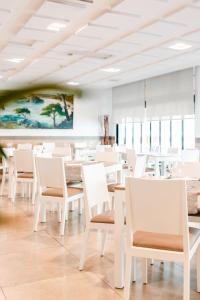 a dining room with white chairs and tables at Hotel Loar Ferreries in Ferreries