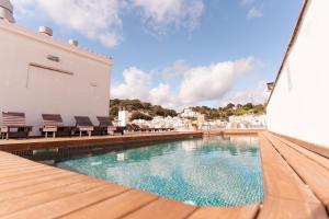 einen Pool mit Stühlen neben einem Gebäude in der Unterkunft Hotel Loar Ferreries in Ferreries