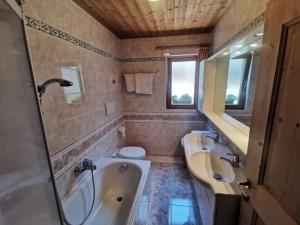 un bagno con due lavandini, una vasca e un WC di Garni Tschutscherhof a Laion