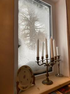 een raam met kaarsen op een plank met een met sneeuw bedekt raam bij Bohemian Chalet in Buşteni