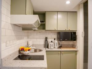a white kitchen with a sink and a microwave at Super comfy apartment in prime central London in London