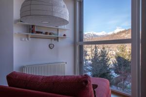 een woonkamer met een rode bank en een groot raam bij Bright loft near Bohinj lake in Bohinj