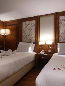 Orient MS Grand Rose في الأقصر: سريرين في غرفة بها مصباحين وهاتف