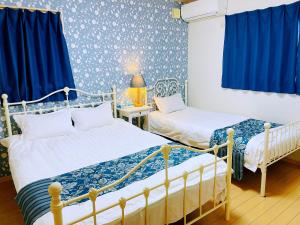 two beds in a room with blue and white wallpaper at 無料駐車場 3階建て一軒家 家族グループ最適 3寝室ヴィラ Usj 道頓堀 難波近い 子連れ歓迎 in Osaka