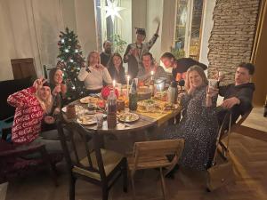 Un grupo de personas sentadas alrededor de una mesa con un árbol de Navidad en Friends Hostel en Tiflis