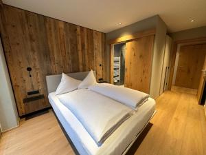 a large white bed in a room with wooden walls at Resort Schrofenblick in Mayrhofen