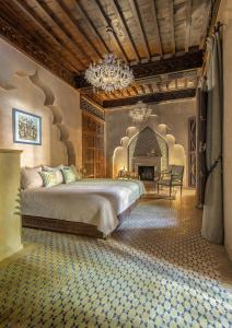 una camera con un grande letto e un lampadario a braccio di La Sultana Marrakech a Marrakech Altre 37 foto