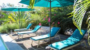 een groep stoelen en parasols naast een zwembad bij Tee-K Lodge Tamarindo in Tamarindo