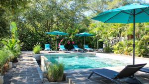 una piscina con sillas y sombrillas junto a una piscina en Tee-K Lodge Tamarindo, en Tamarindo