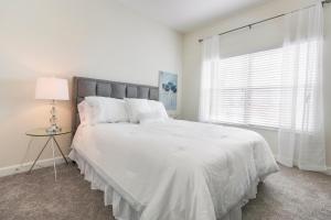 - une chambre avec un grand lit blanc et une fenêtre dans l'établissement 4 Bedrooms 3 Bathrooms Champions Gate 8967 Sd, à Orlando
