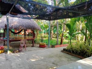 a pavilion with a table and a chair in a garden at Eecfc Home Stay(VHS) in Phumĭ Ta Rós