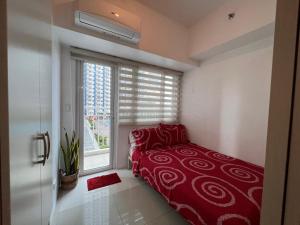 1 dormitorio con cama roja y ventana en Studio Units at SM Light Residences Condo Beside Boni MRT Station, en Manila