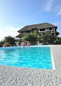 two people in a swimming pool in front of a house at 765 Breezebay suites in Watamu