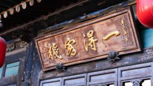 a sign on the side of a building with gold writing at Pingyao Yide Hotel in Pingyao