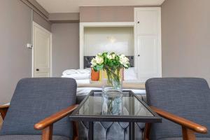 ein Wohnzimmer mit 2 Stühlen und einer Vase mit Blumen auf dem Tisch in der Unterkunft Modern Apartment next to Hyde Park in London