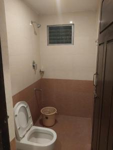 a small bathroom with a toilet and a window at Hotel Alankar in Kanyakumari