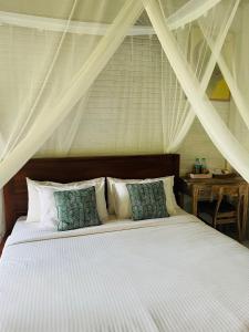 a bedroom with a bed with white sheets and pillows at Depong House in Ubud