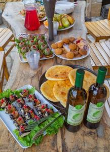einen Tisch mit Teller mit Lebensmitteln und zwei Flaschen Wein in der Unterkunft Guest House Okropilauri in Shuakhevi