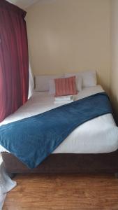 Una cama blanca con una manta azul encima. en 13 Maitland Road, en King Williamʼs Town