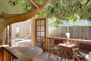 a porch with a bed and a table and a tree at Hammonds Beach Haven in Santa Barbara