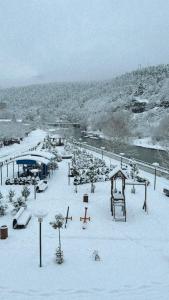 a snow covered park with a playground and a river at Vitali Apartment in Borjomi