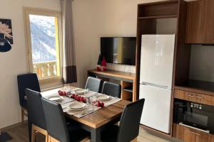 kuchnia ze stołem z krzesłami i białą lodówką w obiekcie Refuge des Vues Alpines Isola 2000 w mieście Isola 2000