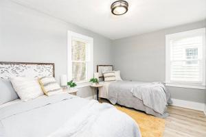 a white bedroom with two beds and two windows at South Bend Serenity: Freshly Renovated 3BR 2mi ND in South Bend