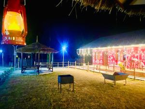 un bâtiment avec un kiosque éclairé la nuit dans l'établissement The Birsani cafe and resort, à Jhājra