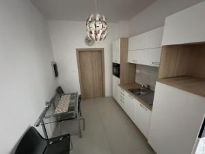 a small kitchen with a glass table and a chandelier at Apartmán Lodenica in Piešťany