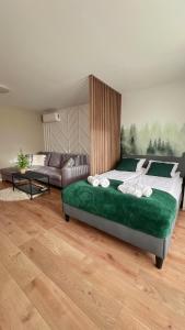 a bedroom with a large green bed and a couch at Gojka Apartamenty in Piekielnik