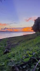 a sunset over the water with a field of grass at Amullya Kanan Villa in Haldia