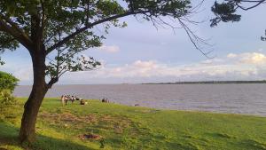 a group of people sitting on the grass near the water at Amullya Kanan Villa in Haldia