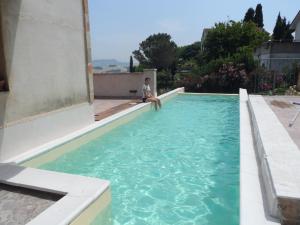 a person sitting on the edge of a swimming pool at Il Piccolo Carro Apartments in Monterubbiano