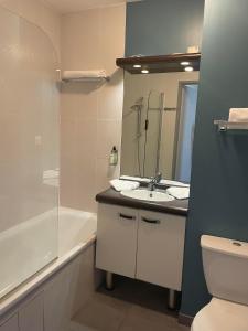 a bathroom with a sink and a toilet and a tub at Hôtel Résidence Les Pins Galants in Tournefeuille