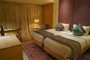 um quarto de hotel com uma cama grande e uma secretária em Hotel Royal Orchid Jaipur, Tonk Road em Jaipur