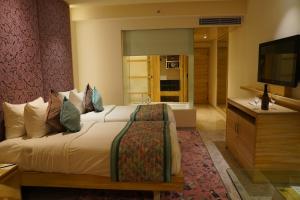 una camera d'albergo con letto e TV di Hotel Royal Orchid Jaipur, Tonk Road a Jaipur