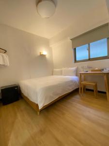 Schlafzimmer mit einem weißen Bett und einem Schreibtisch in der Unterkunft 宏洲旅社HZ Hotel in Taipeh