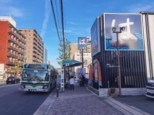 京都的住宿－秋桜館Cosmos，停在城市街道上的一个公共汽车站的公共汽车