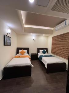 2 bedden in een kamer met 2 bedden, waarvan 1 tweepersoonsbed en 1 eenpersoonsbed. bij Sky Suite in Islamabad